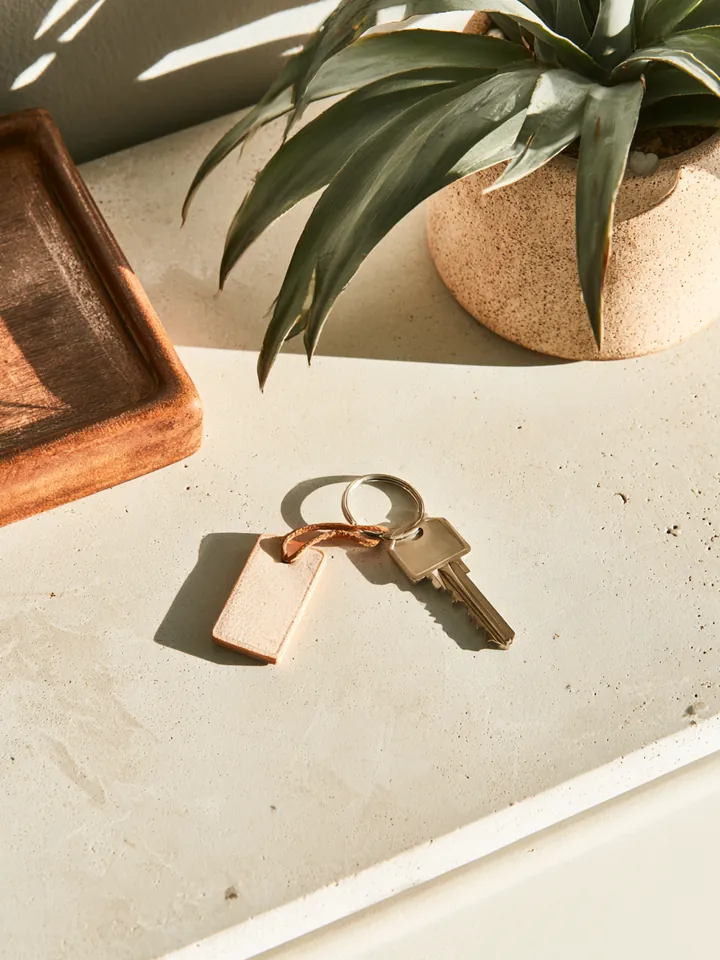 Single key ring with a leather keychain on a light entryway console, representing a vehicle pledged as loan collateral