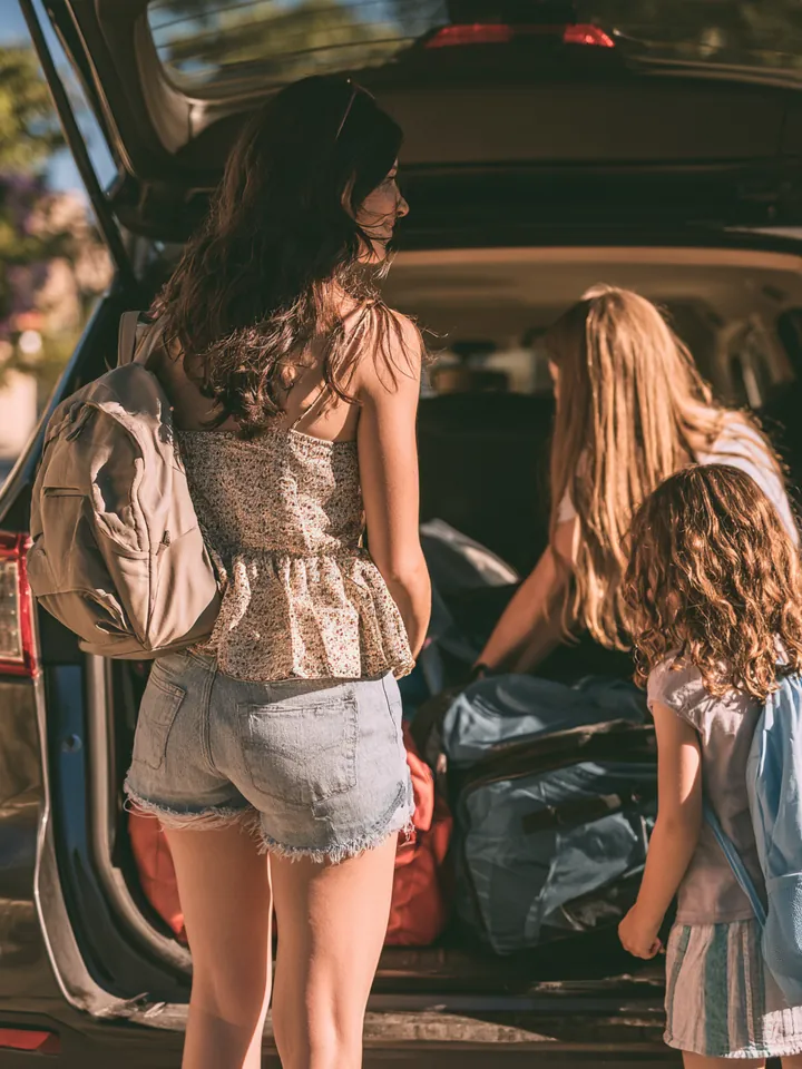 Mom and two kids loading sports bags into an SUV trunk, a family weighing whether a short-term loan fits the budget